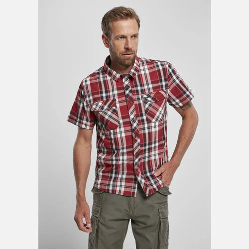 Man wearing a red and white plaid shirt with green cargo pants on a light gray background