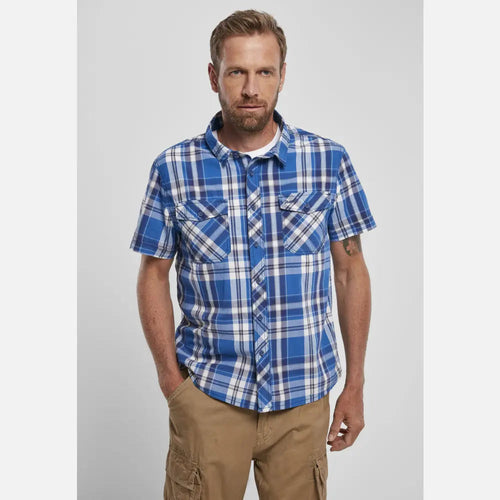 Man wearing a blue plaid shirt and beige pants on a light gray background
