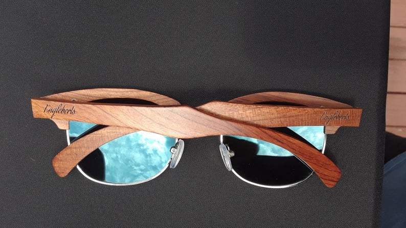 Wooden-framed sunglasses with turquoise lenses on a dark background