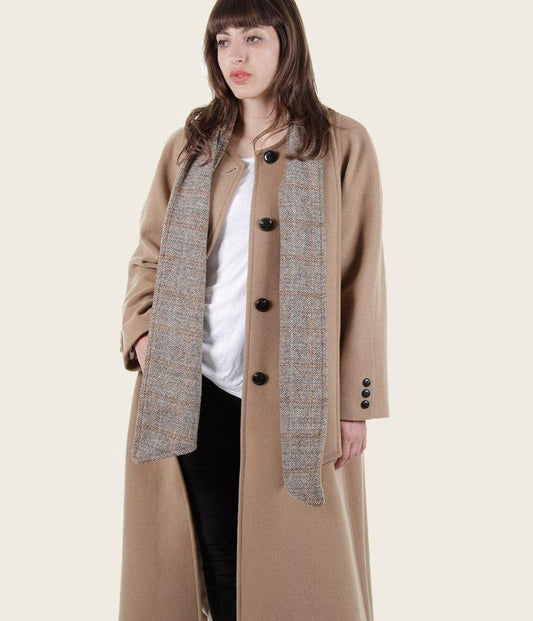 Woman wearing a long beige coat with a patterned inner lining on a white background