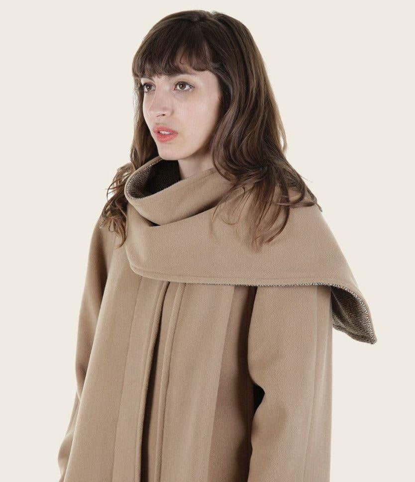 Woman wearing a beige coat with a plain background