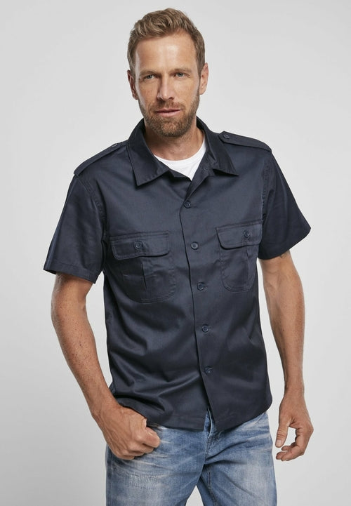Man wearing a navy short-sleeve shirt with pockets on a light gray background
