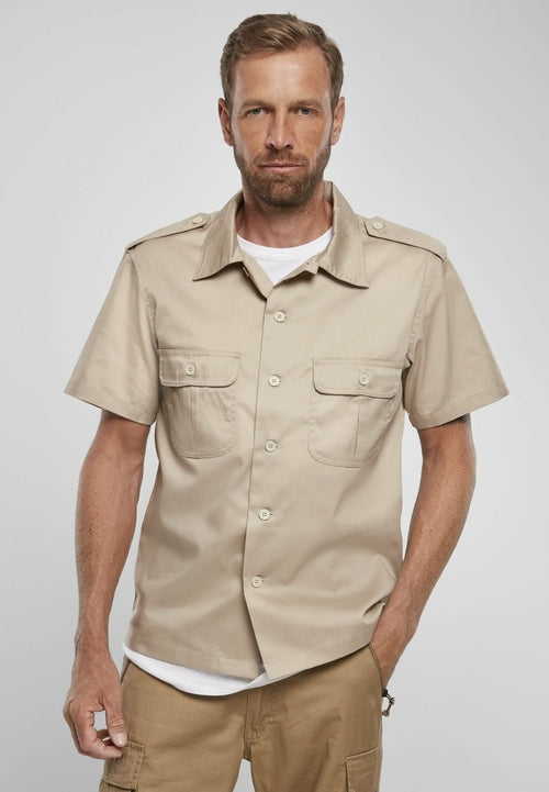 Man wearing a beige short-sleeve shirt with pockets on a white background