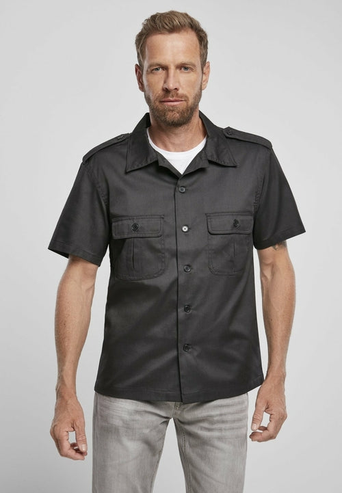 Man wearing a black short-sleeve shirt with pockets on a gray background