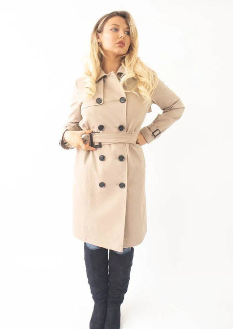 Woman wearing a beige trench coat with black buttons on a white background