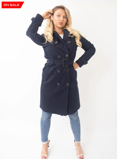 Woman wearing a navy trench coat on a white background
