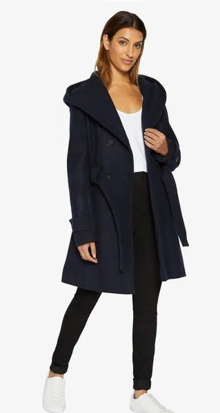 Woman wearing a navy coat with a white background.