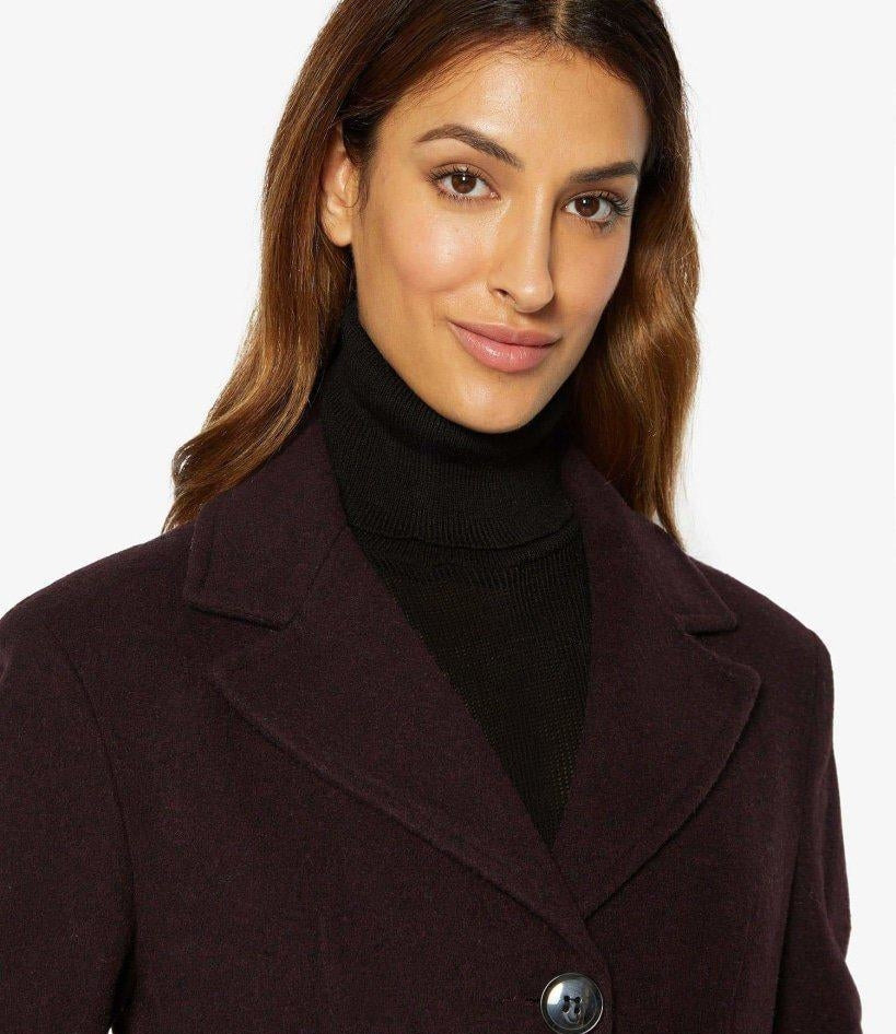 Woman wearing a dark coat with a plain background