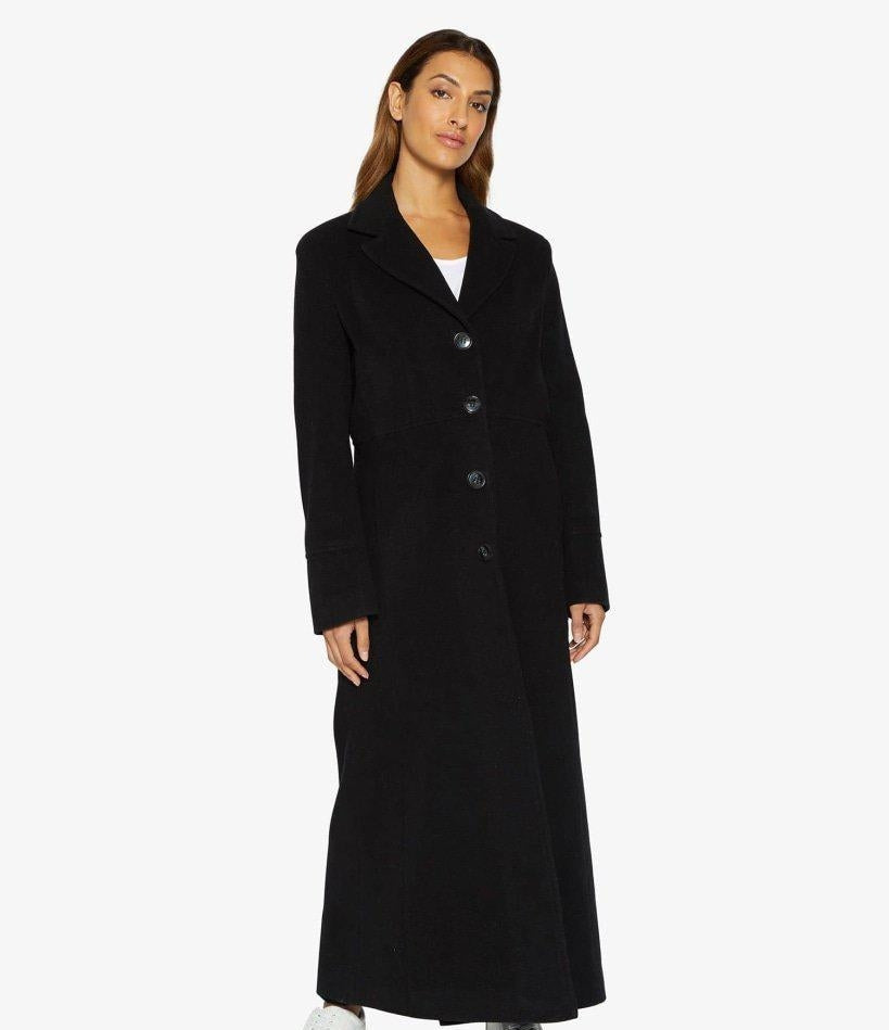 Woman wearing a long black coat on a white background