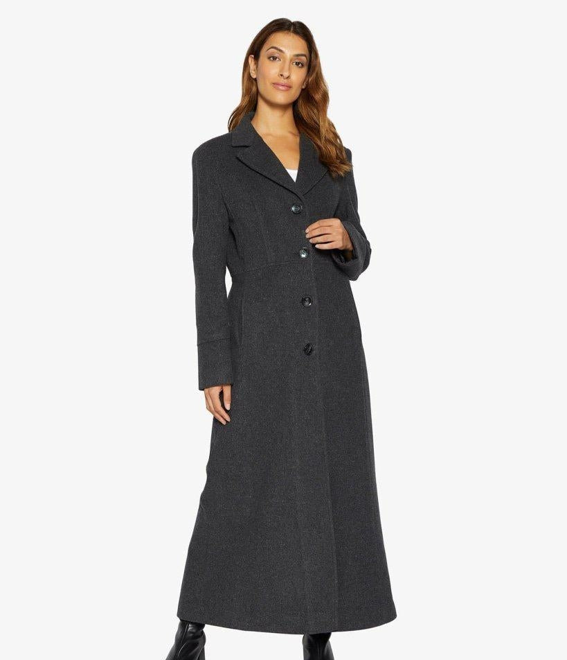 Woman wearing a long dark gray coat on a white background