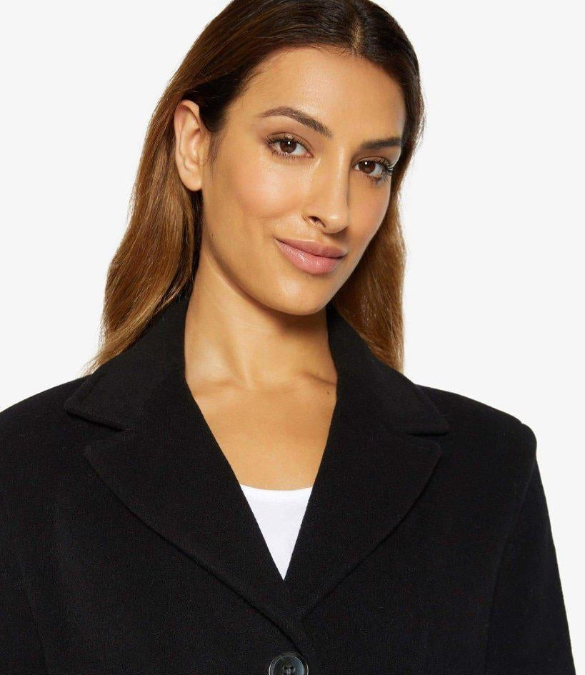 Woman wearing a black coat with a white background