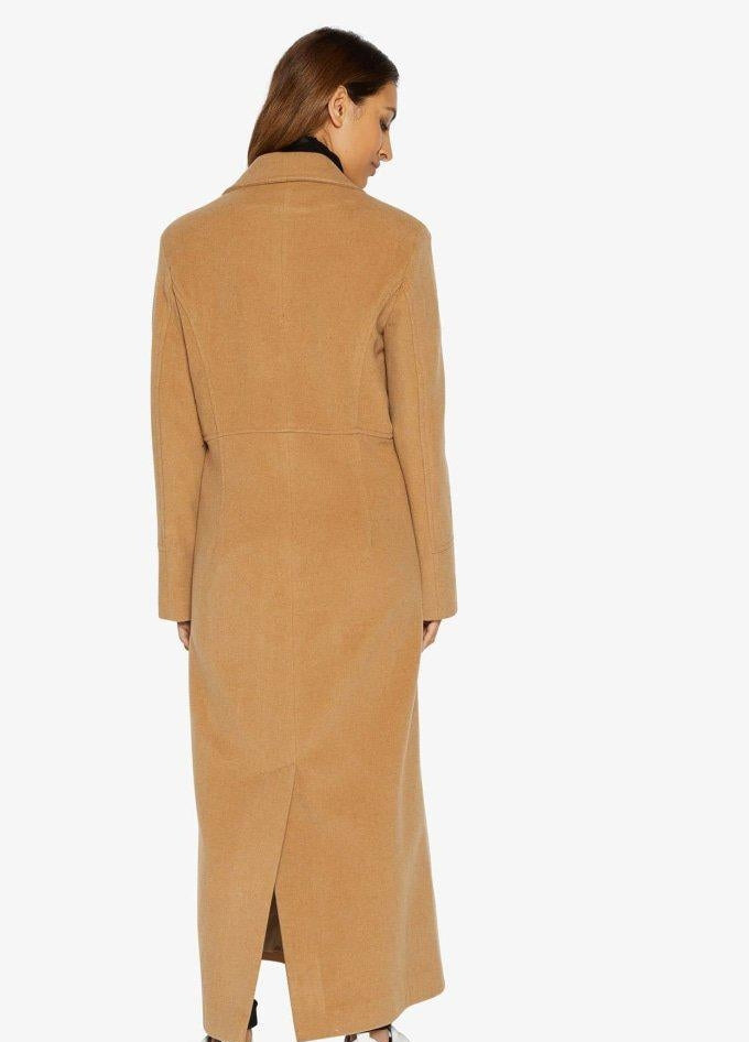 Woman wearing a long tan coat on a white background