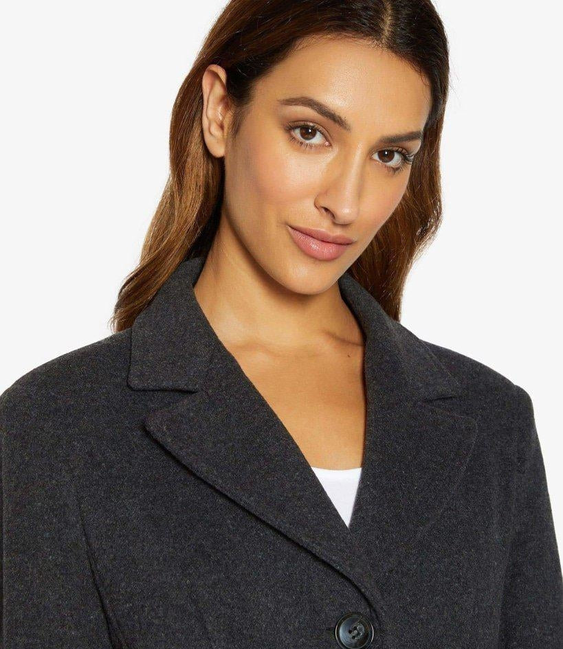 Woman wearing a dark gray coat with a plain background