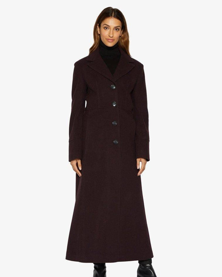 Woman wearing a long dark coat on a white background