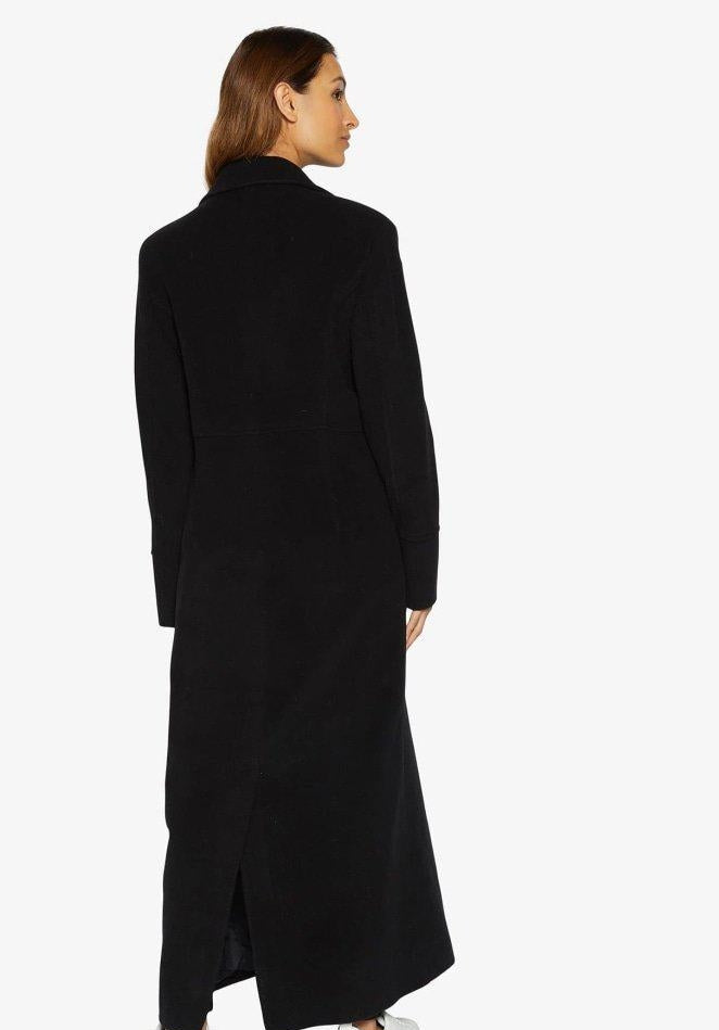 Woman wearing a black coat on a white background