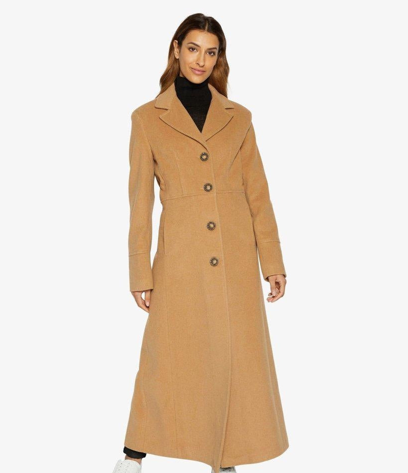 Woman wearing a long beige coat on a white background