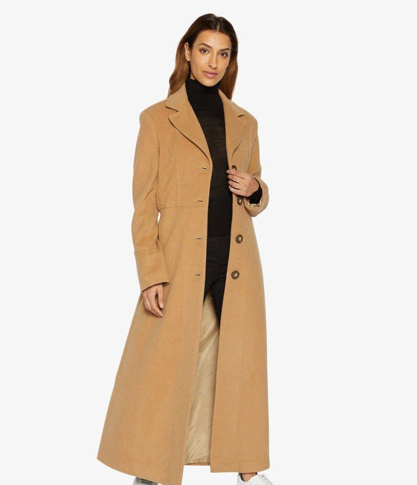 Woman wearing a long beige coat on a white background