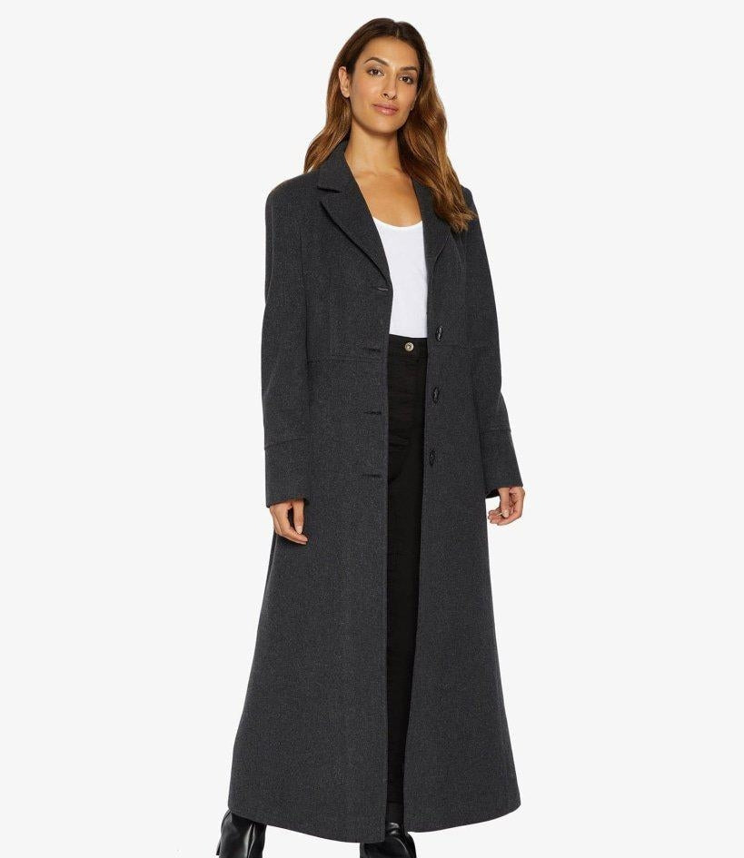 Woman wearing a long dark gray coat on a white background