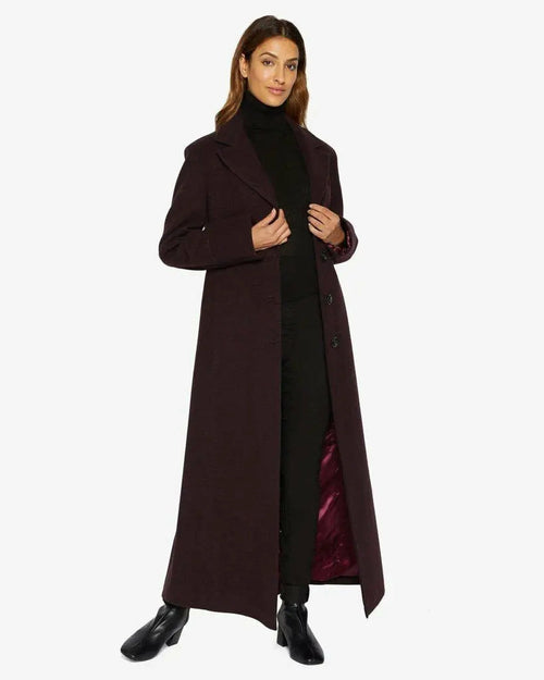 Woman wearing a long dark coat on a white background