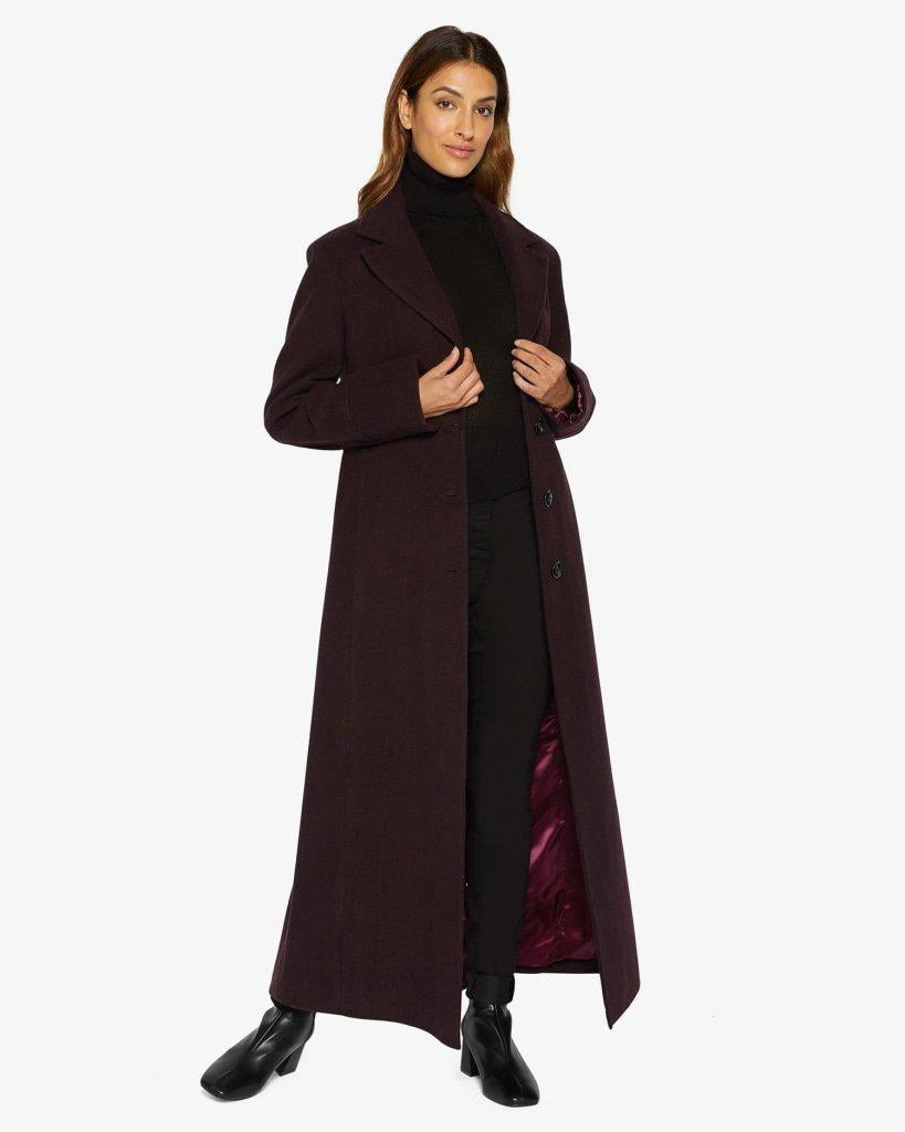 Woman wearing a long dark coat on a white background