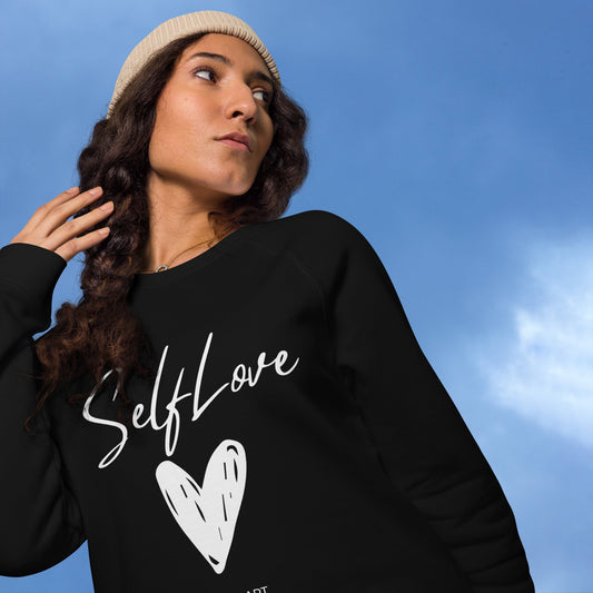 Person wearing a black sweatshirt with 'Self Love' and a heart design against a blue sky.