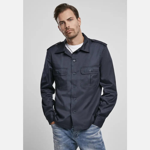 Man wearing a navy blue jacket and jeans on a light gray background