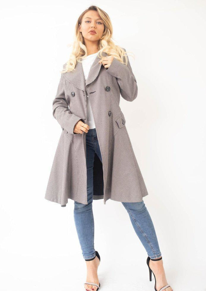 Woman wearing a long gray coat over a white top and blue jeans on a white background.