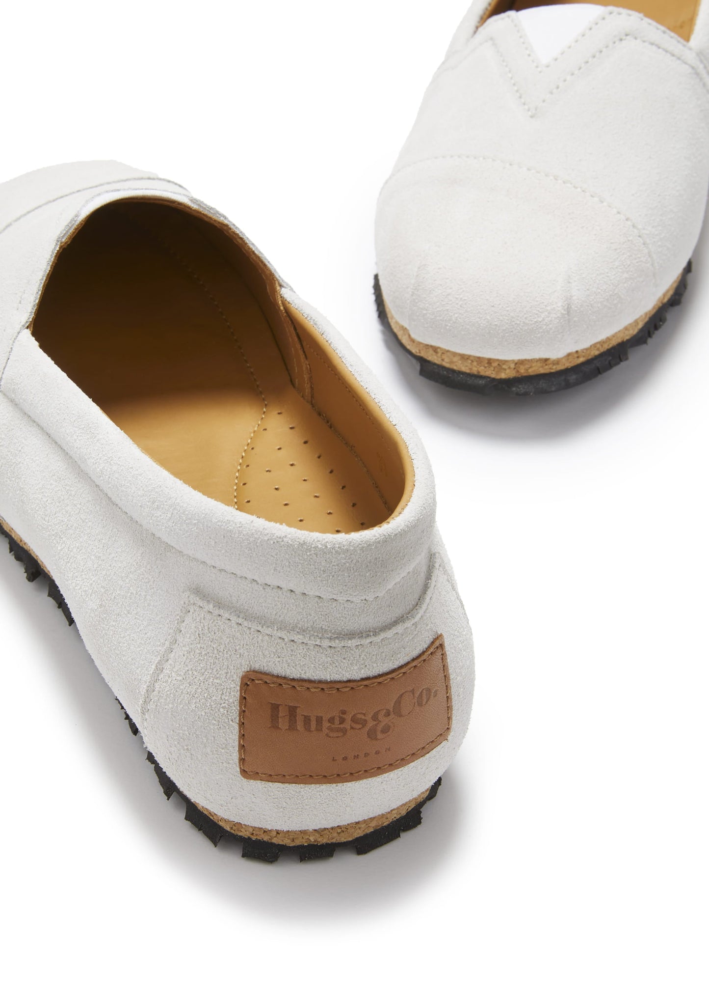White loafers with brown sole and 'Hugs' label on a white background