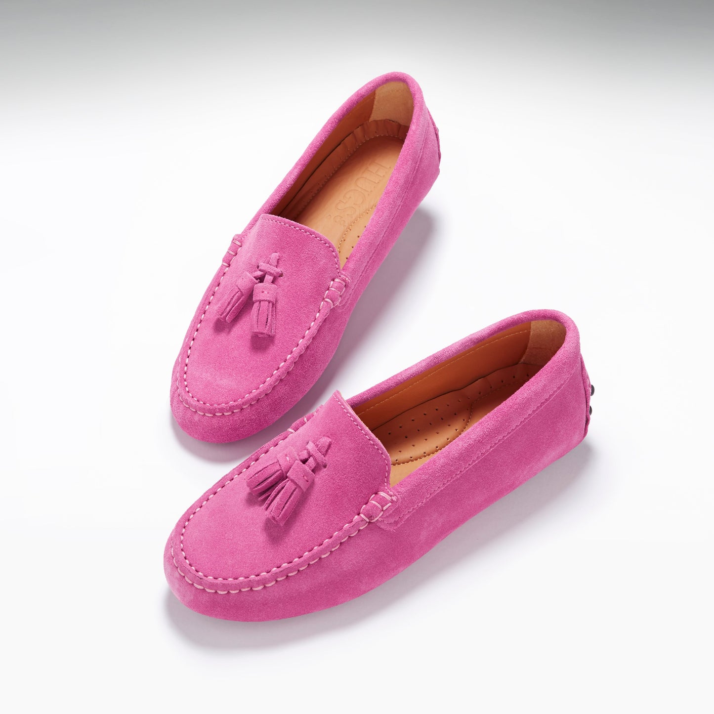 Pair of pink loafers with tassels on a white background