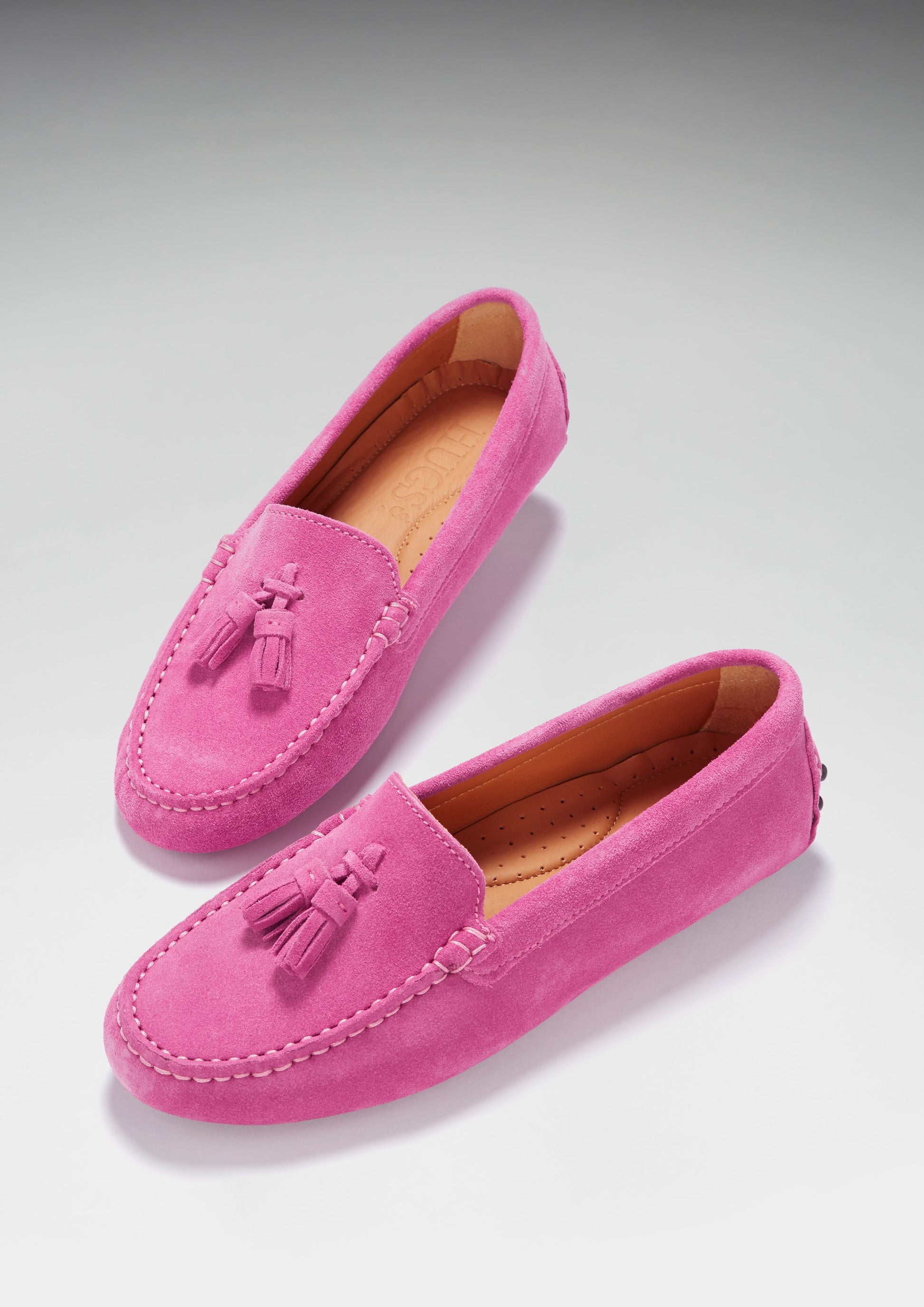 Pair of pink loafers with tassels on a light gray background