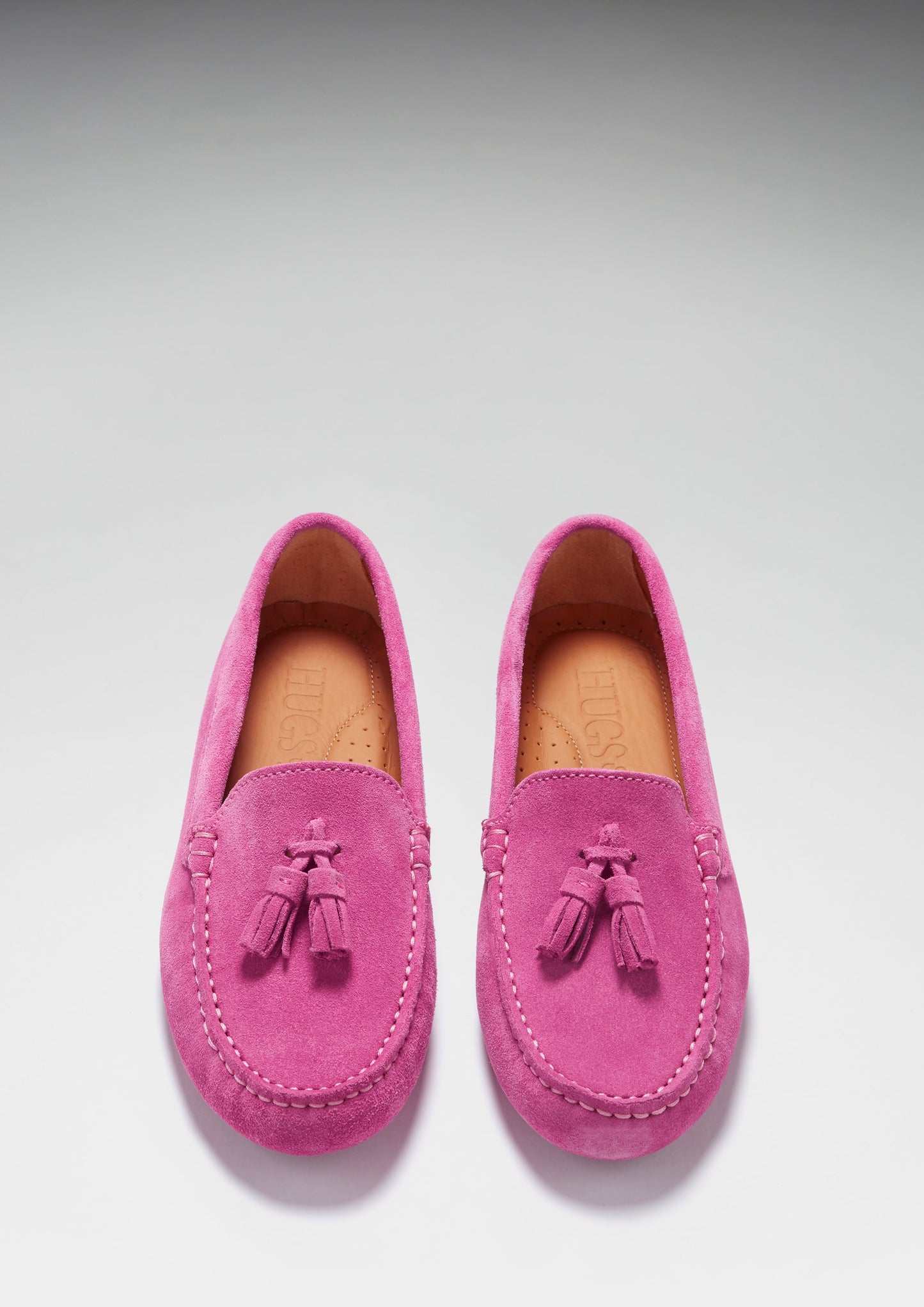 Pair of pink loafers with tassels on a light gray background