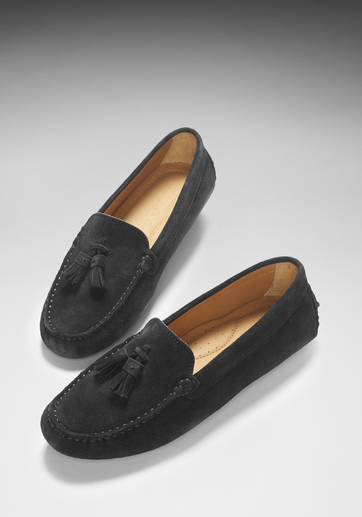 Pair of black loafers with tassels on a gray background