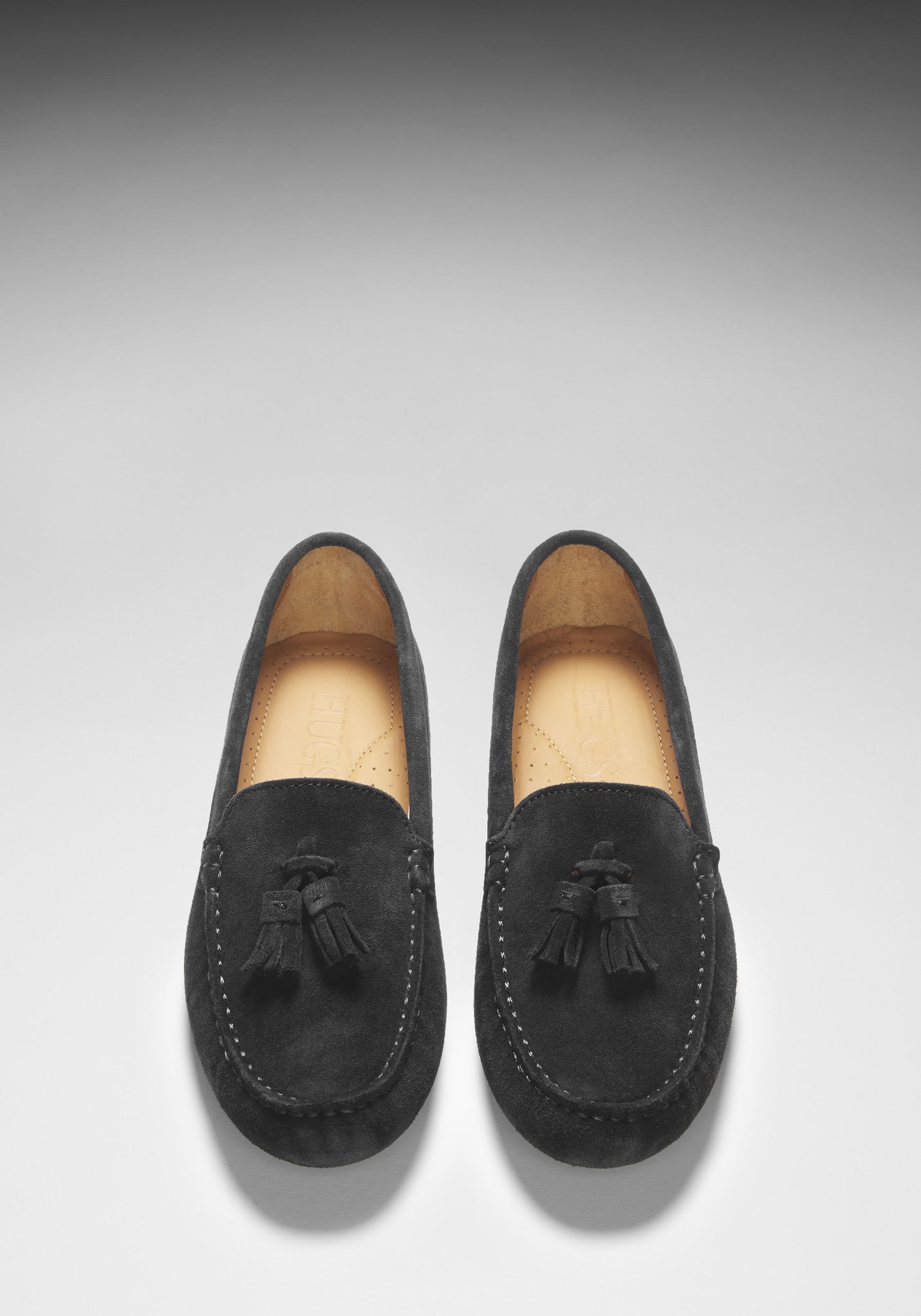 Pair of black loafers with tassels on a light gray background