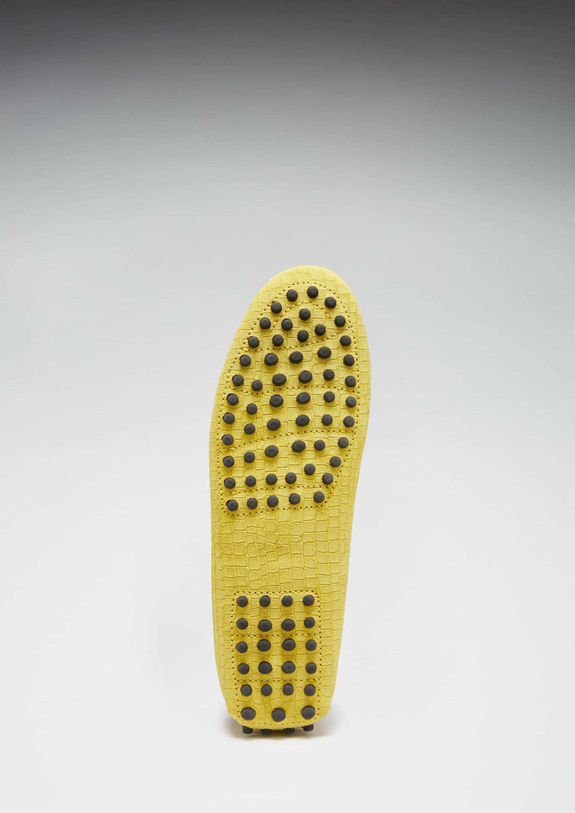 Yellow shoe insole with textured sole on a gray background