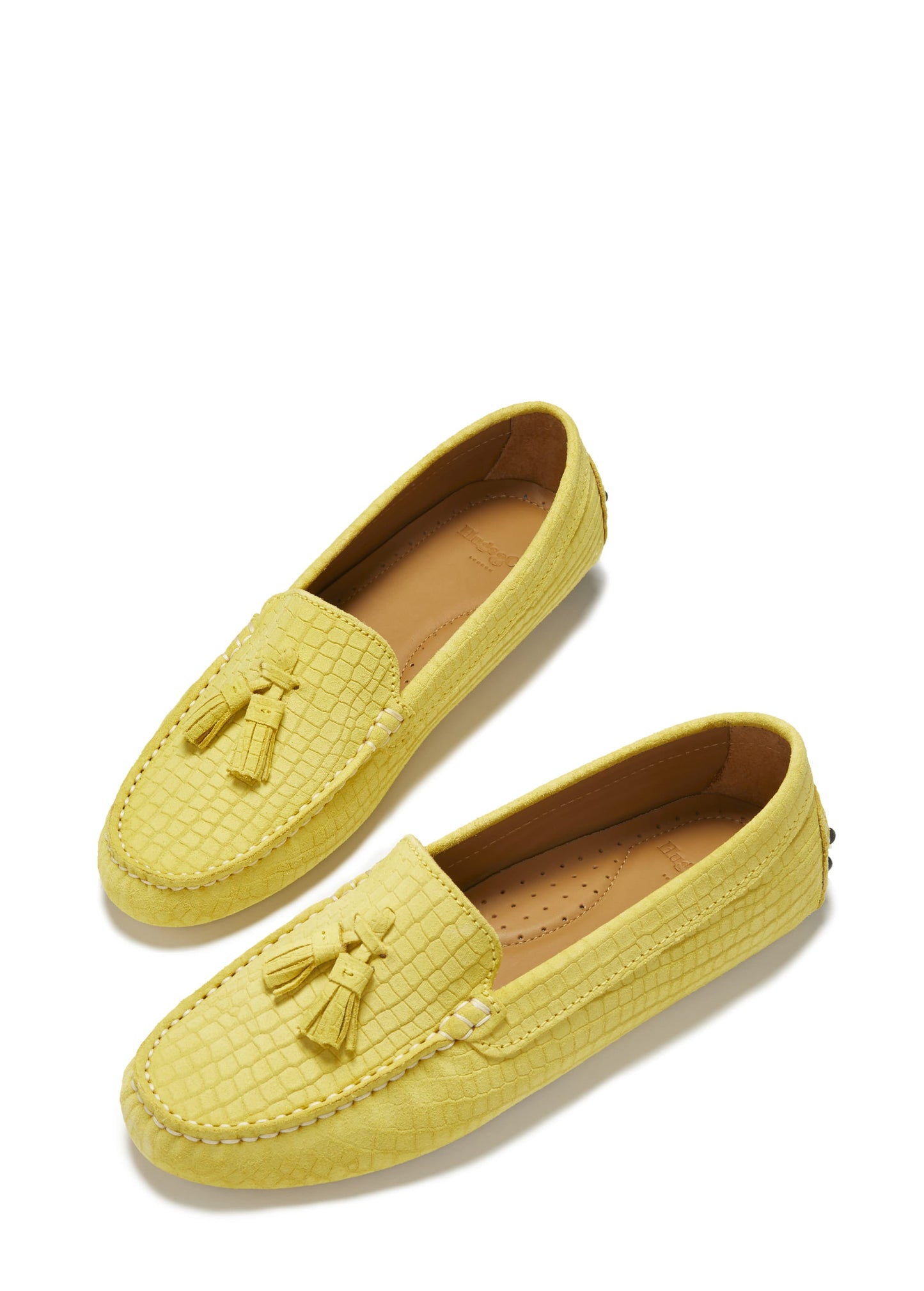 Pair of yellow loafers with tassel details on a white background