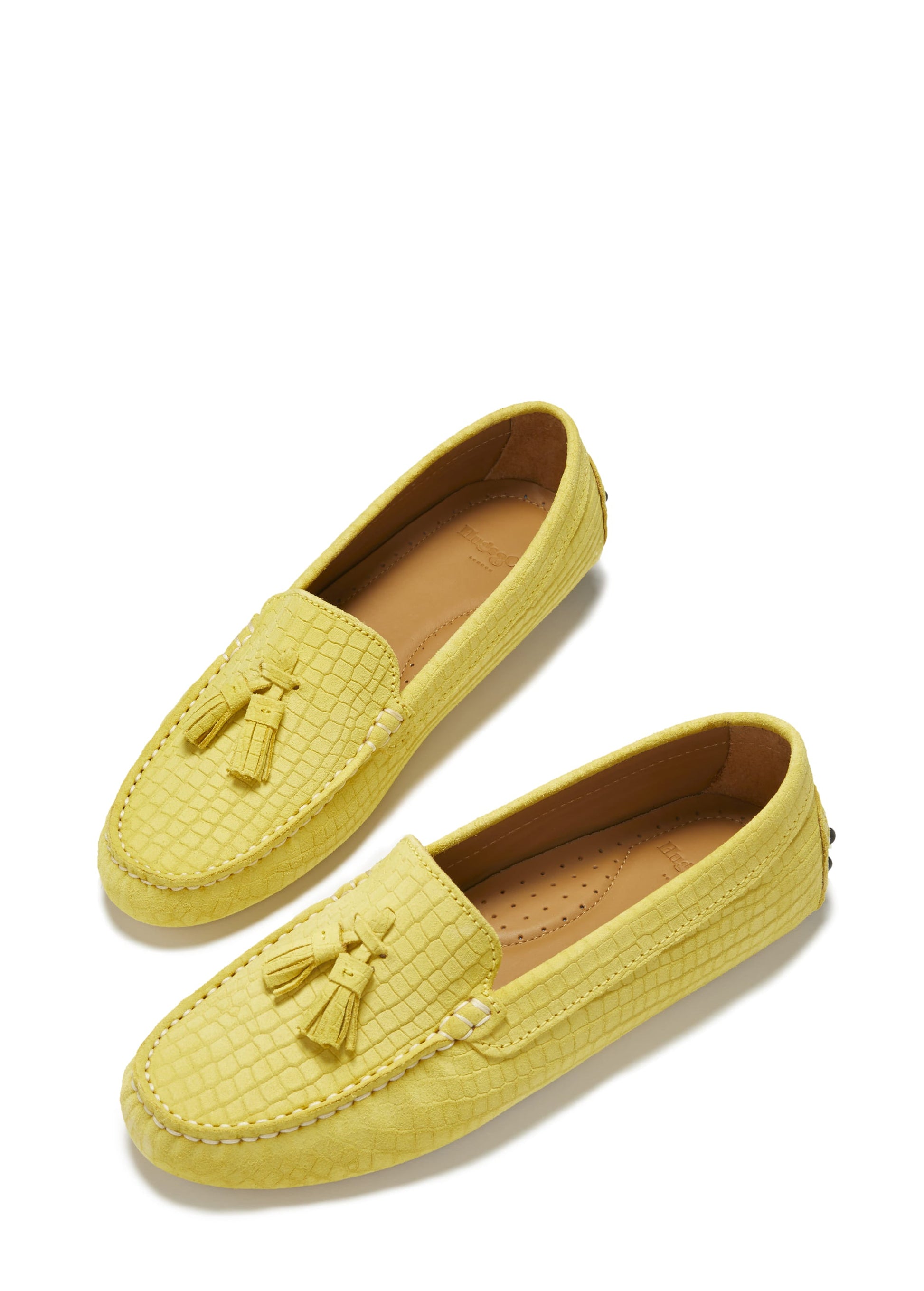 Pair of yellow loafers with tassel details on a white background