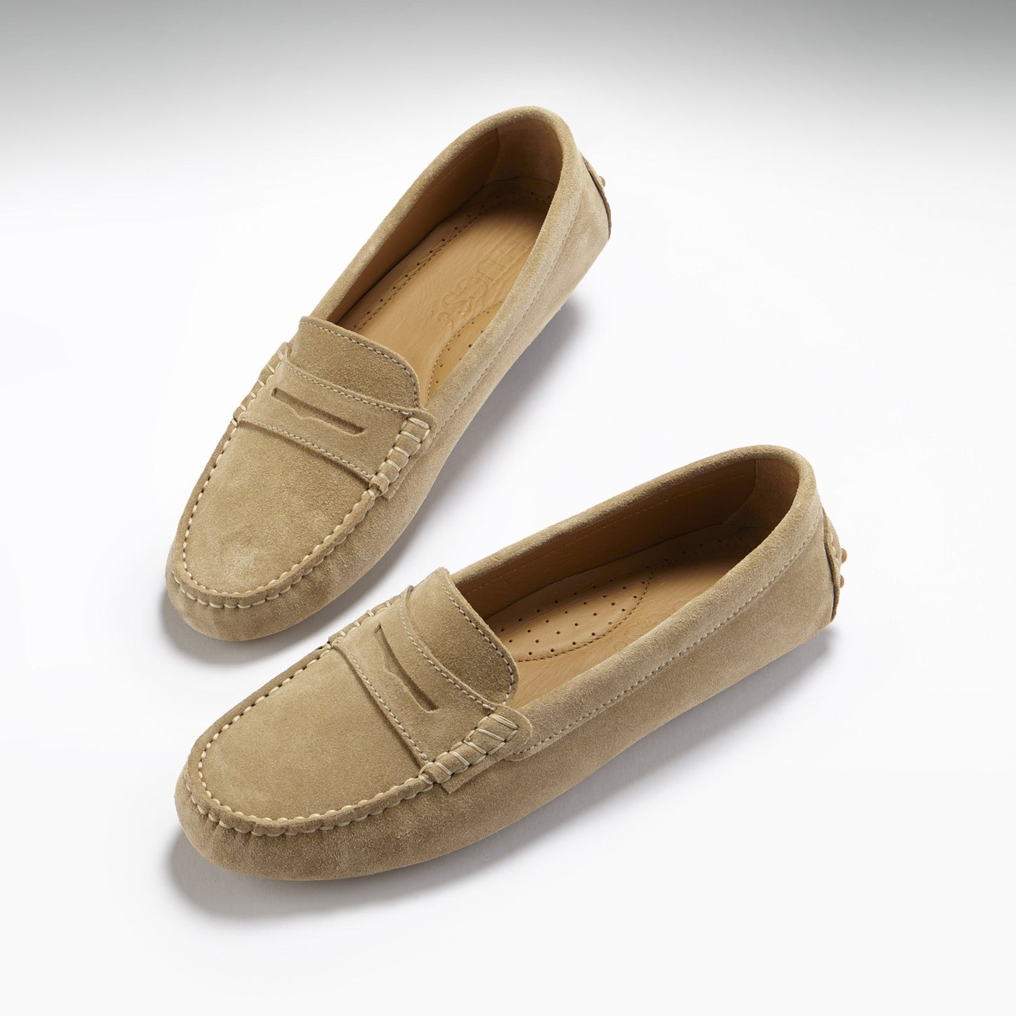 Pair of beige loafers on a light gray background