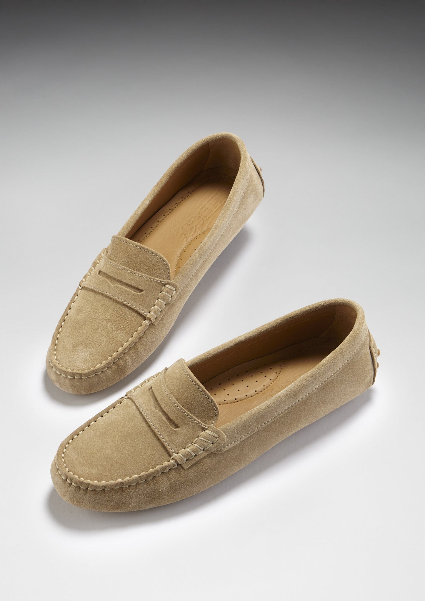Pair of beige loafers on a light gray background