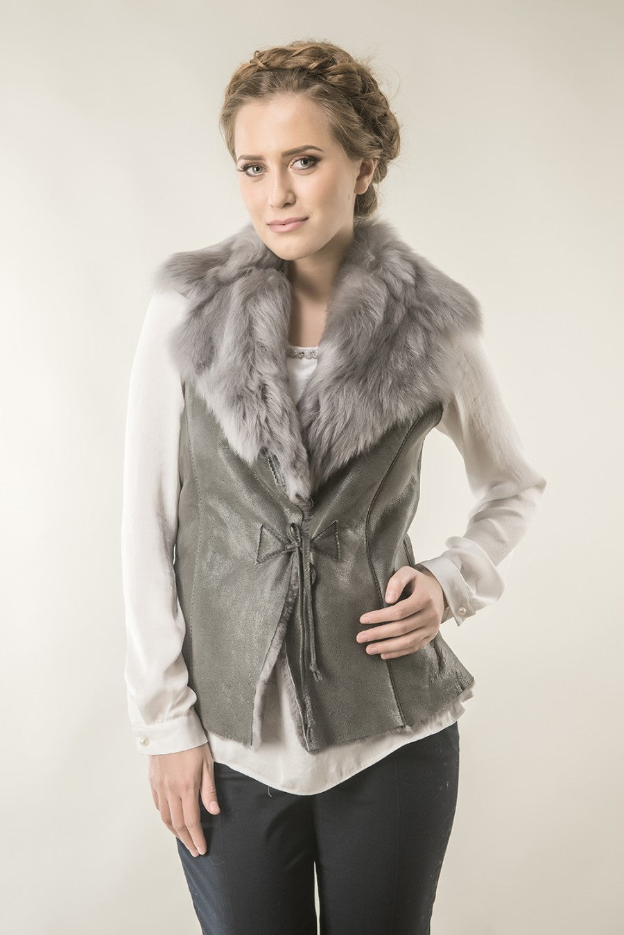 Woman wearing a gray vest with fur collar against a plain background