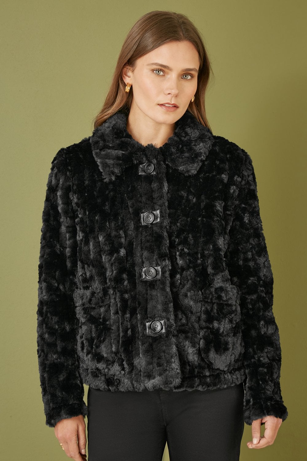 Woman wearing a black faux fur jacket on an olive green background