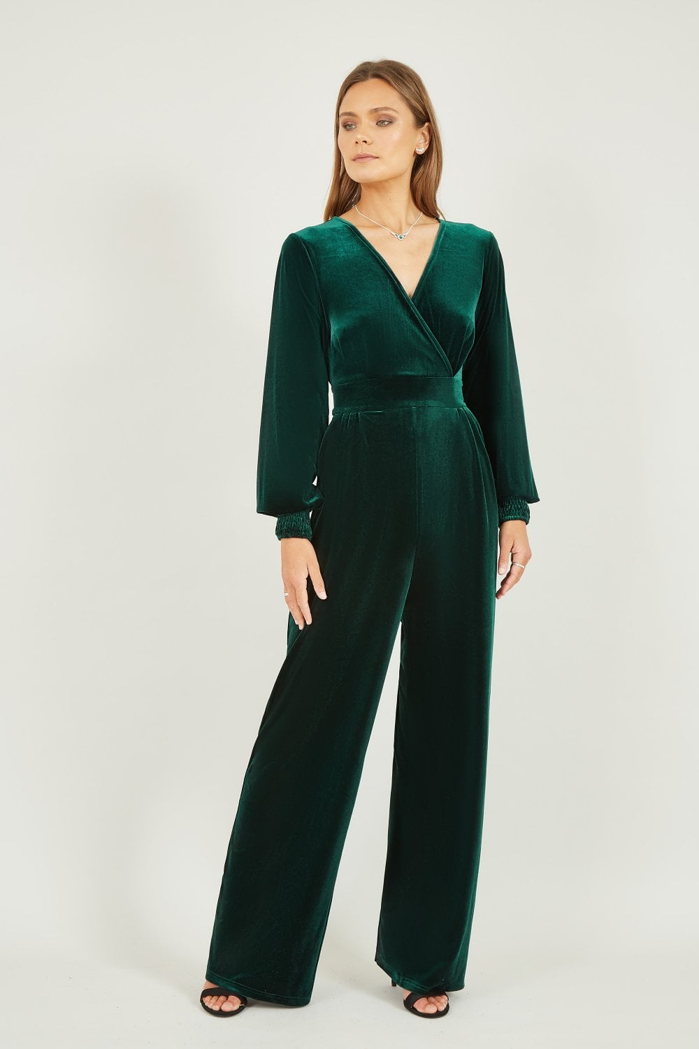 Woman wearing a green velvet jumpsuit on a white background