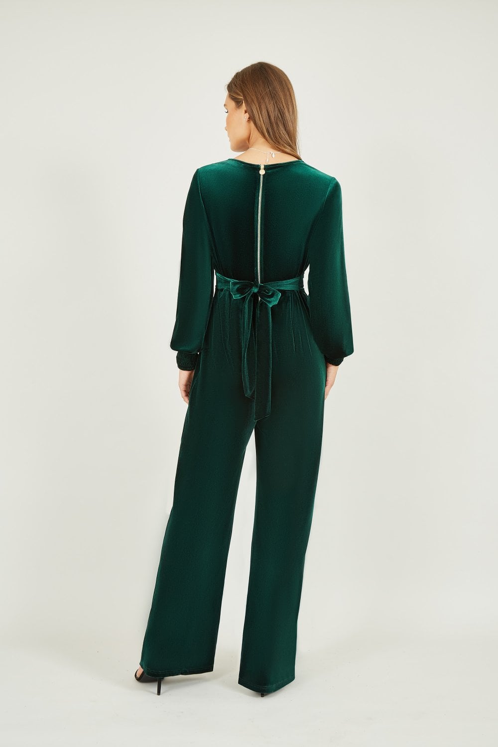 Woman wearing a green jumpsuit with a belt on a white background