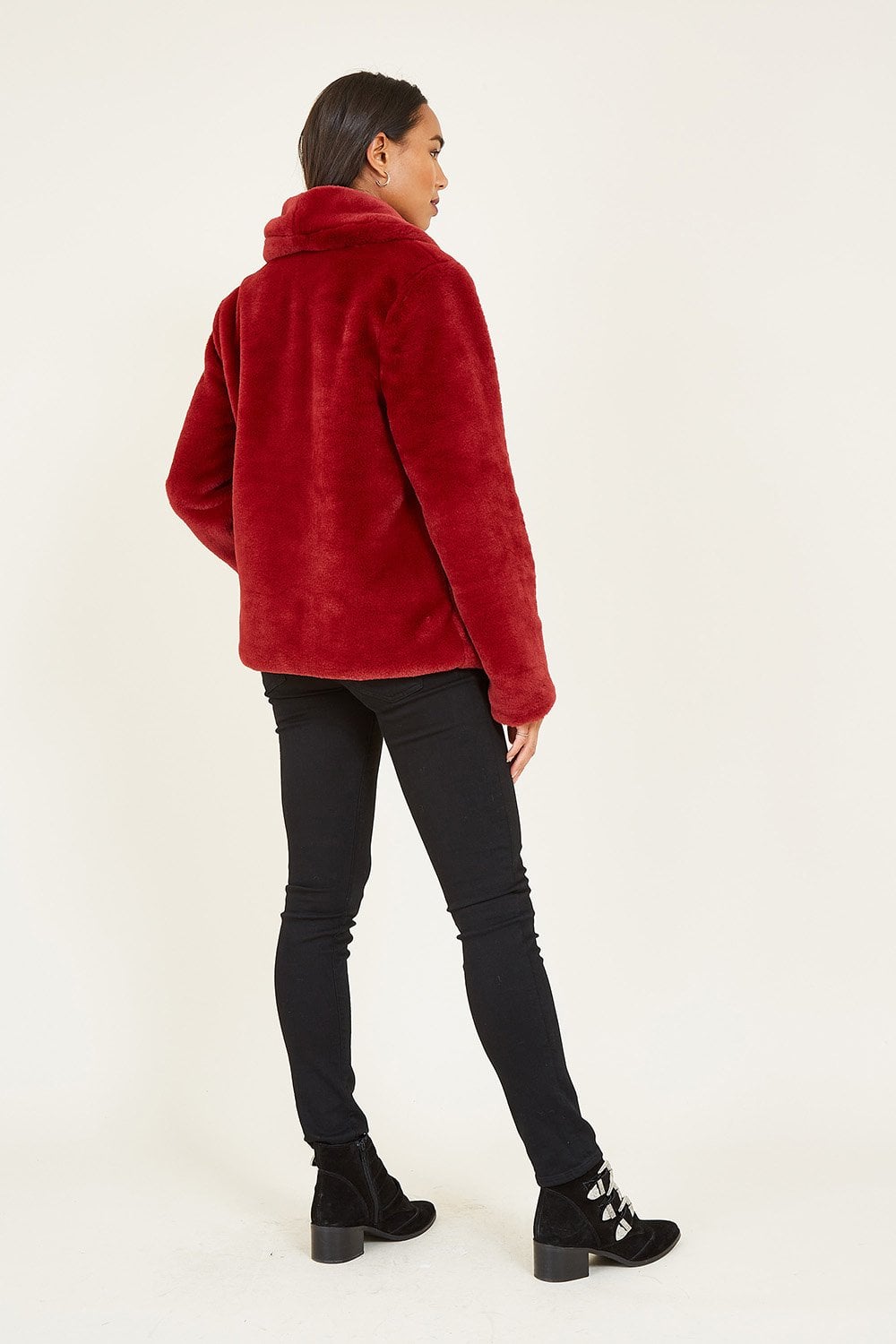 Person wearing a red faux fur jacket on a white background